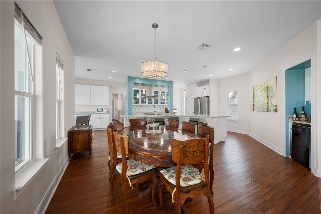 Dining room with a carved wooden table and chairs beside a bright kitchen with turquoise accents.