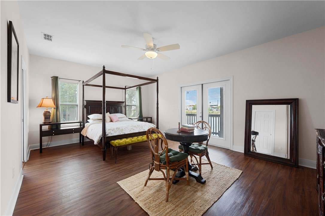 Bedroom with a dark four-poster bed, round table and chairs, and glass doors to a balcony.