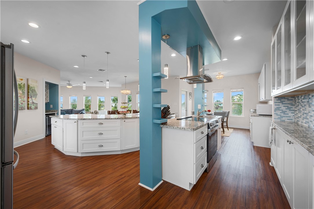 Open kitchen with white cabinets, granite counters, stainless steel appliances, and a blue accent column.
