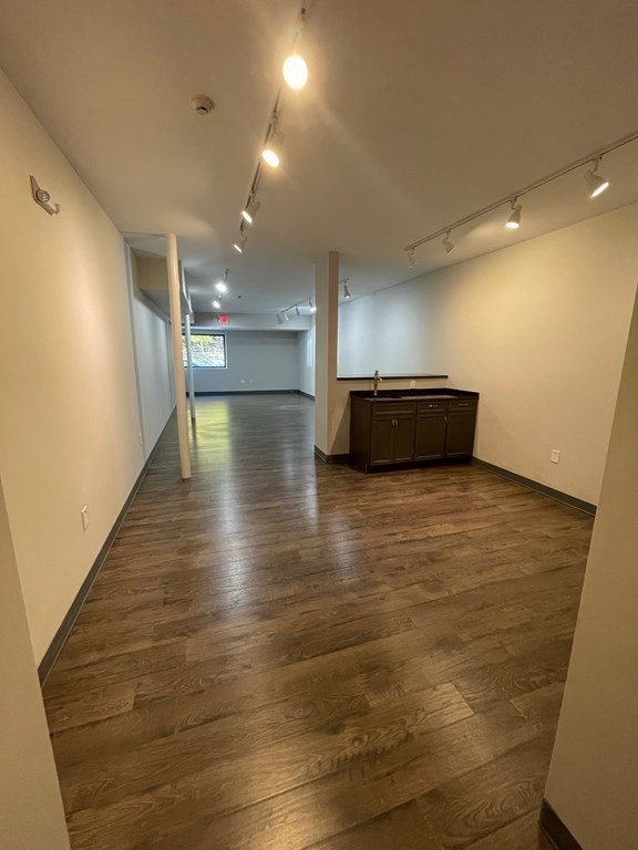 Open interior with wood floors, track lighting, and a small sink cabinet.