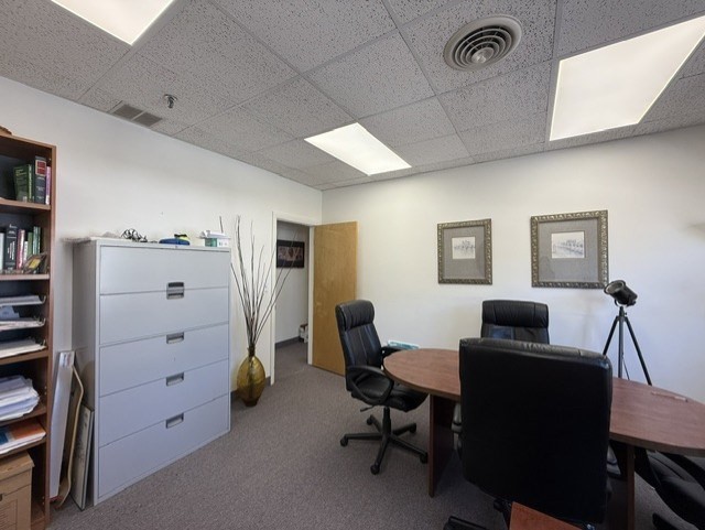 Office with a conference table, black chairs, filing cabinet, and bookshelf.