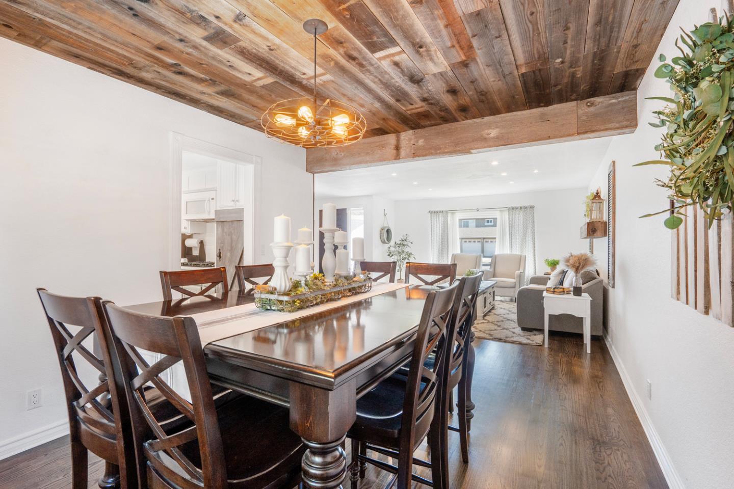 Dining room with a long dark wood table beneath a reclaimed wood ceiling, opening into a living area.
