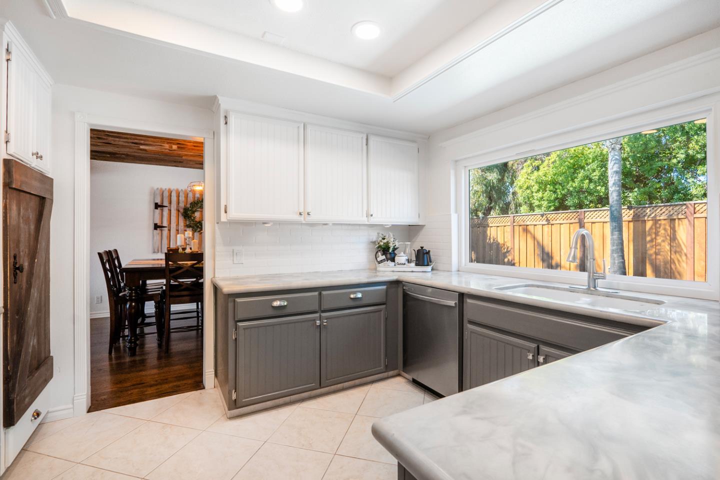 Kitchen with gray cabinets, marble-look counters, and a large window above the sink.