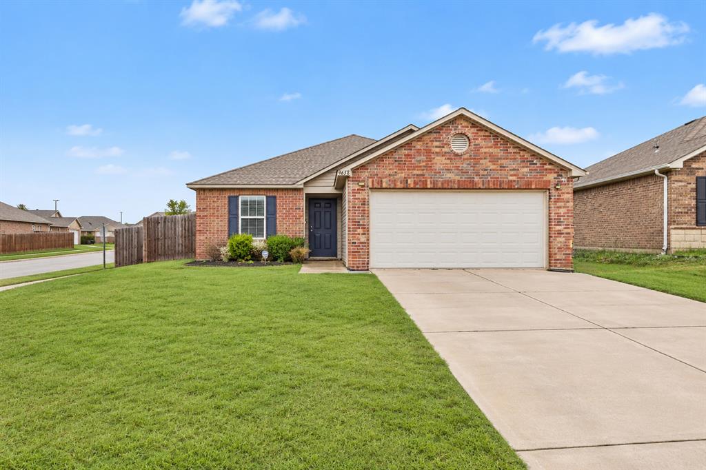 Single-story brick home with a white double garage, blue entry door, and broad concrete driveway.