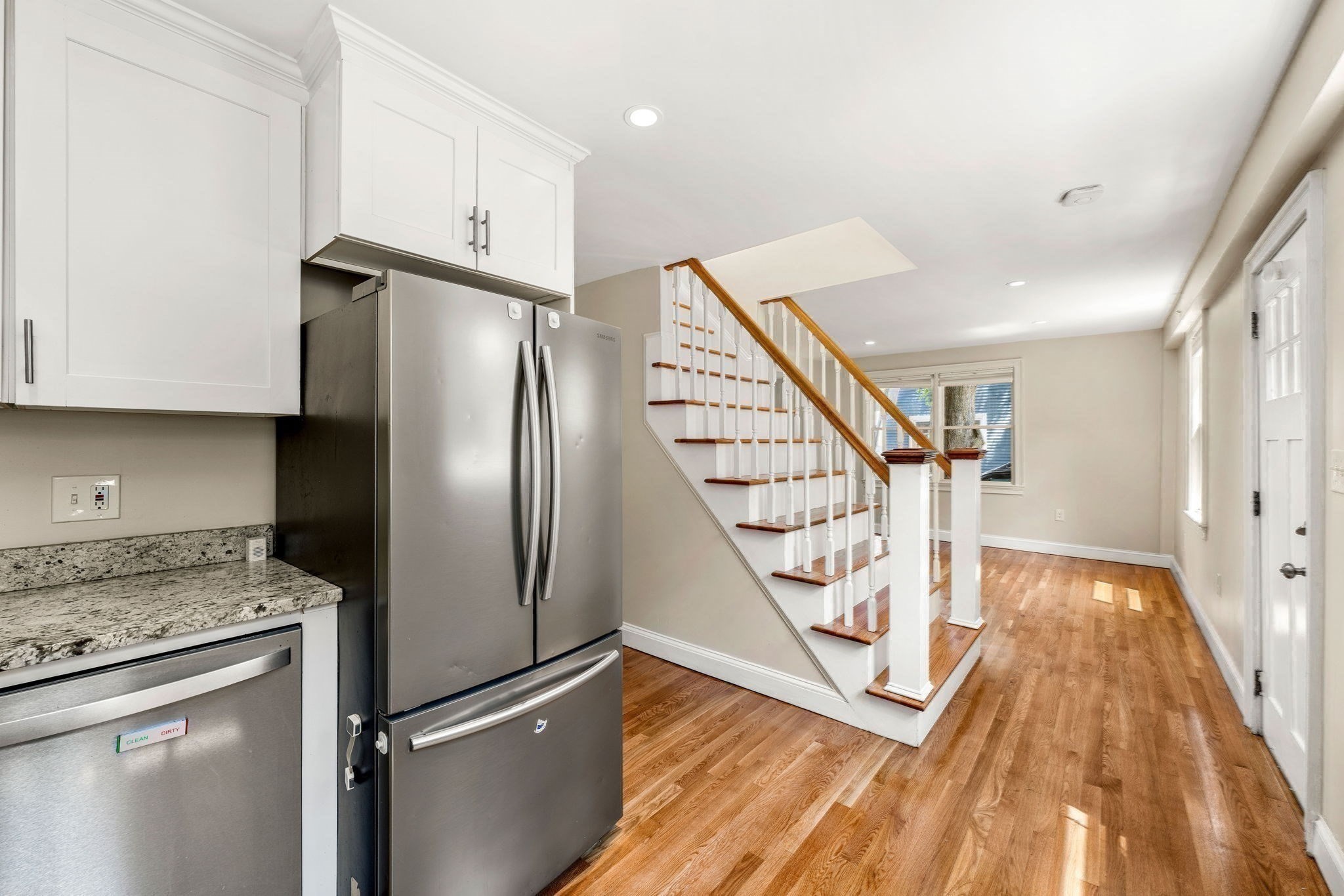 Kitchen with stainless steel appliances and granite counters beside a hardwood staircase.