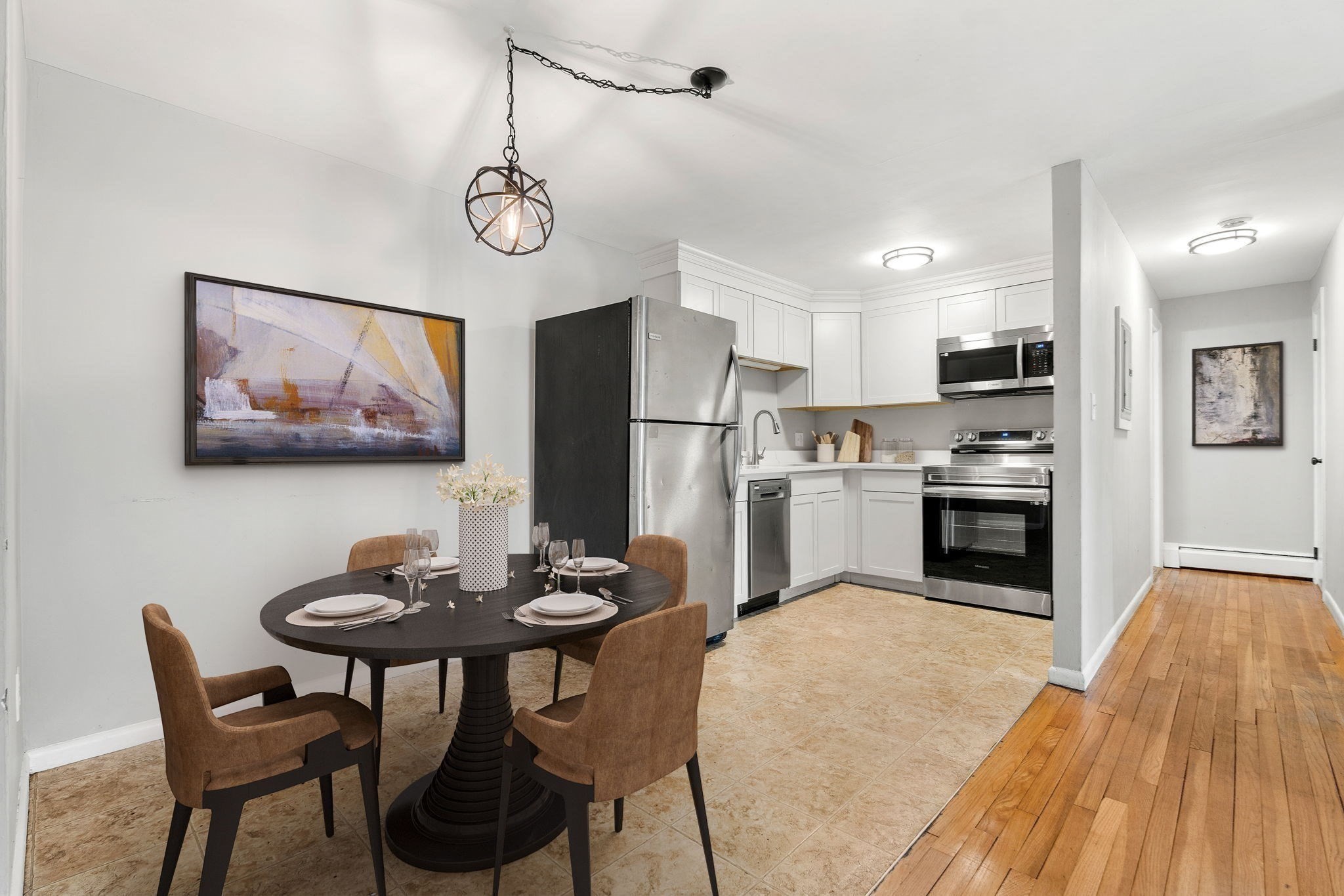 Kitchen and dining area with white cabinets, stainless steel appliances, and a round table set for four.
