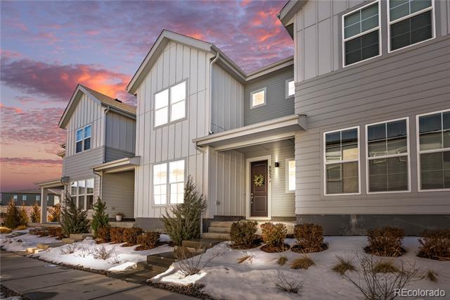 Modern gray home with snow-covered landscaping beneath a pink dusk sky.