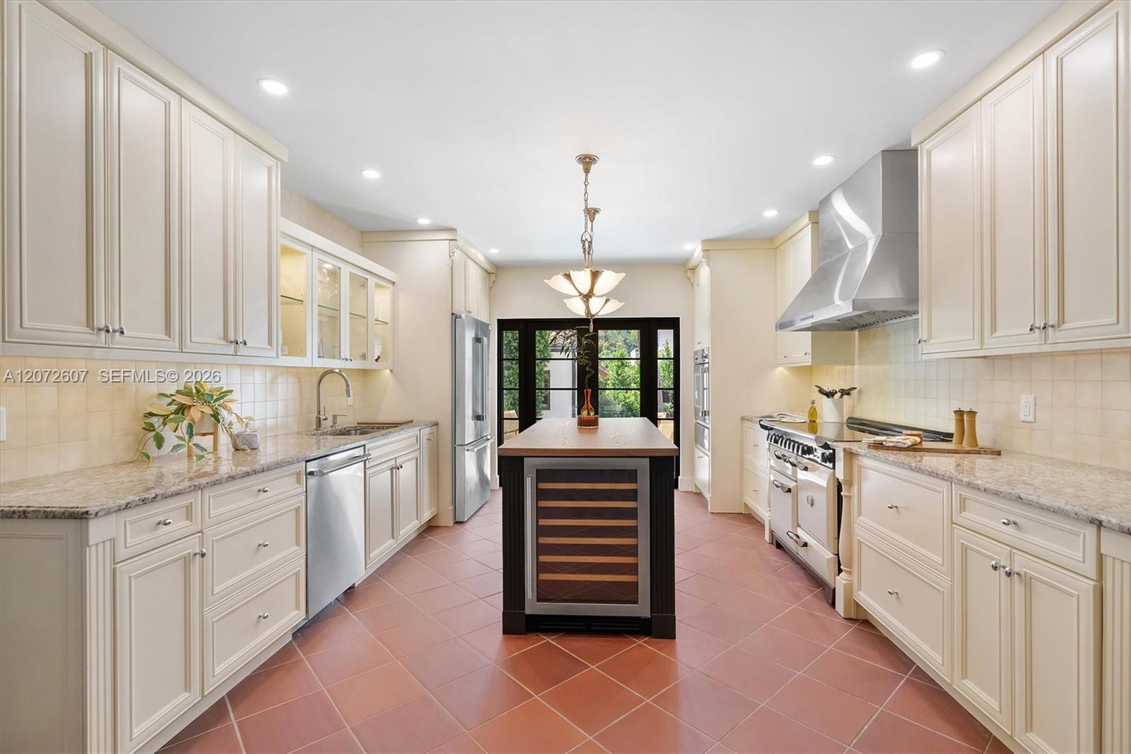 Kitchen with cream cabinetry, granite counters, a dark island, and stainless steel appliances.