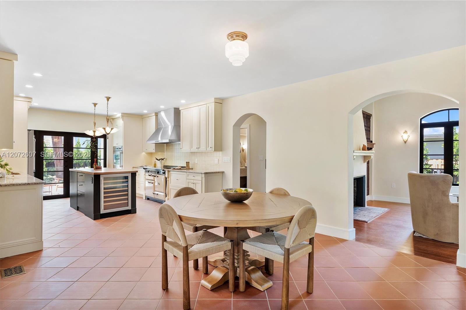Open kitchen and dining area with a round table, white cabinetry, and arched openings.