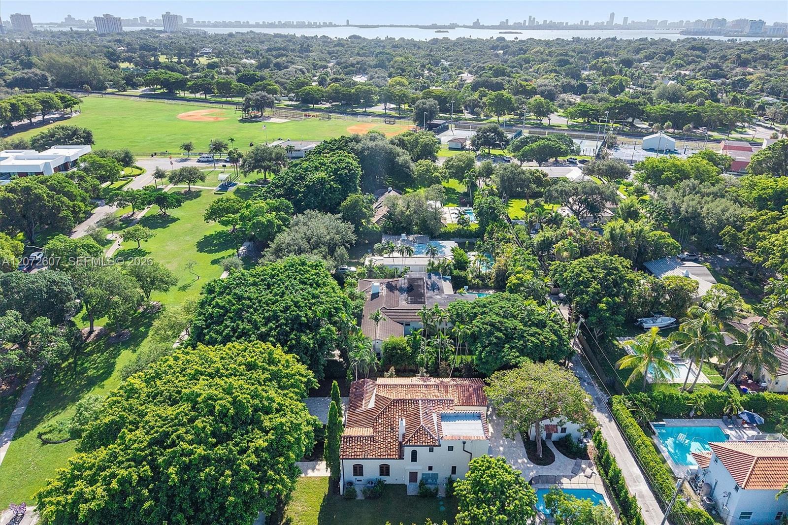 Miami Shores home with a tile roof and pool, near a park, bay, and distant city skyline.