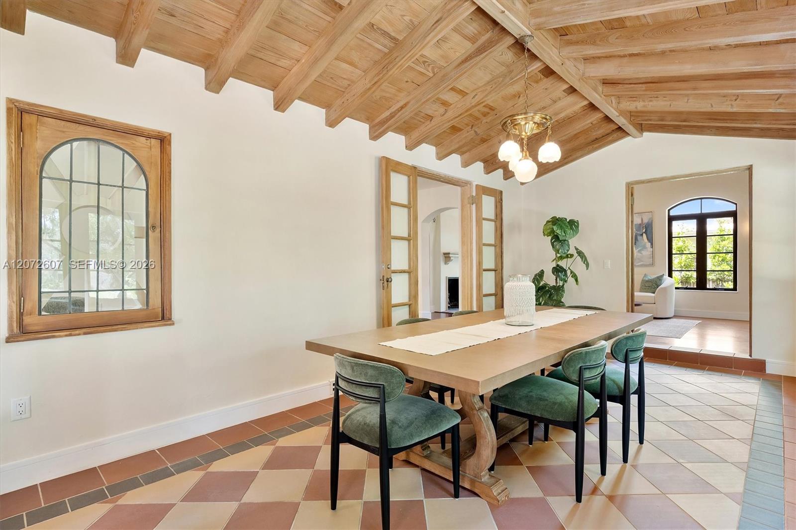 Dining room with a vaulted wood ceiling, patterned tile floor, and a large table with green chairs.