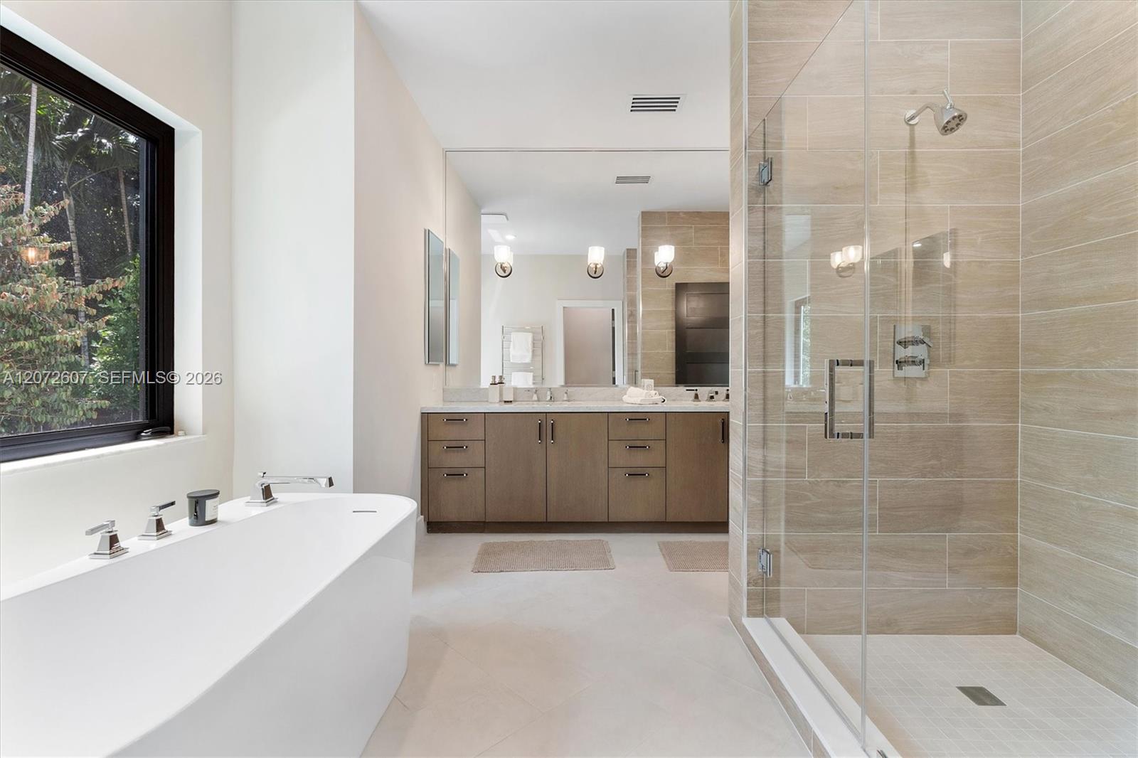 Bathroom with freestanding tub, double vanity, and glass-enclosed tiled shower.