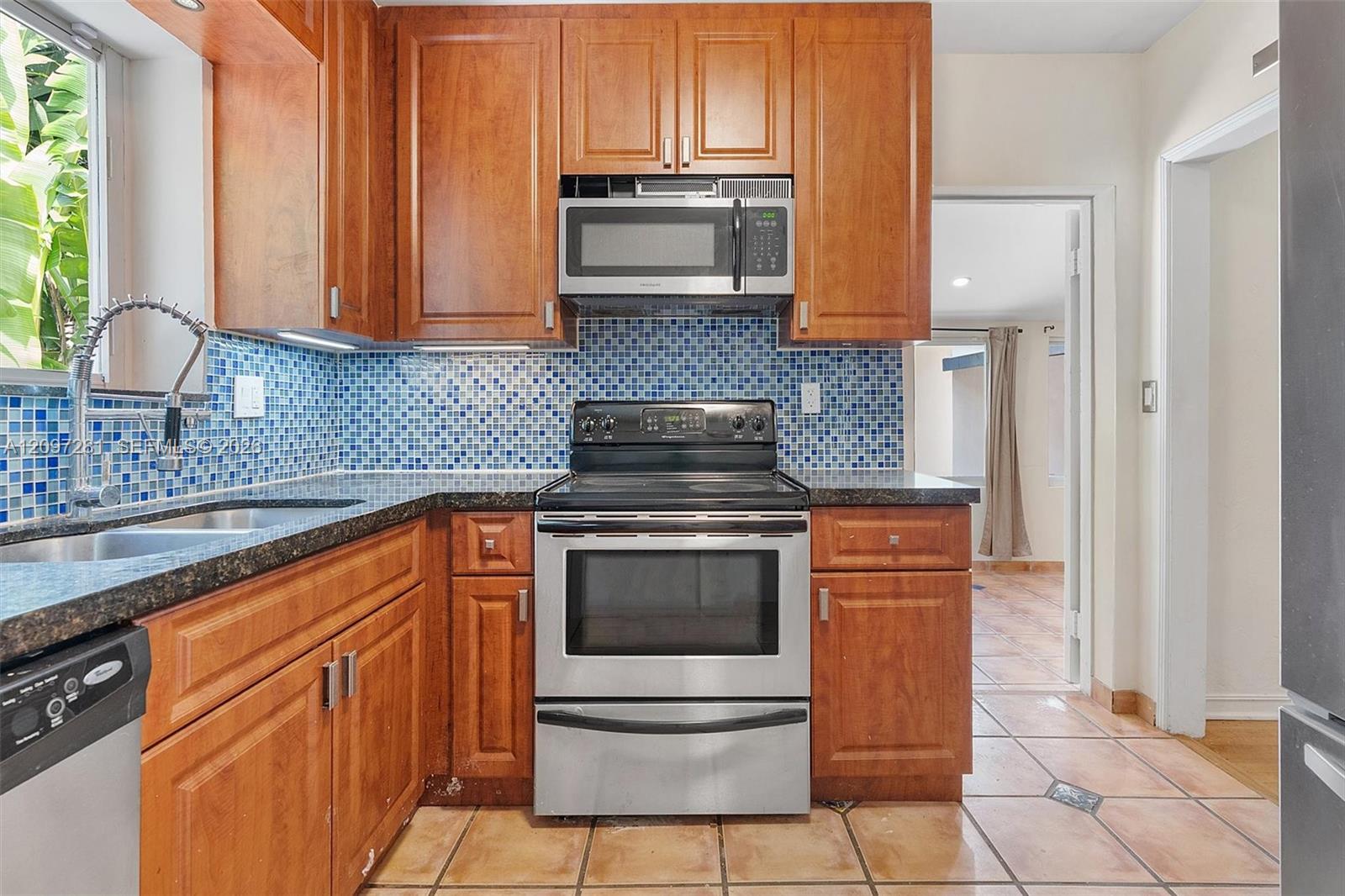 Kitchen with wood cabinets, blue mosaic backsplash, and stainless steel appliances.