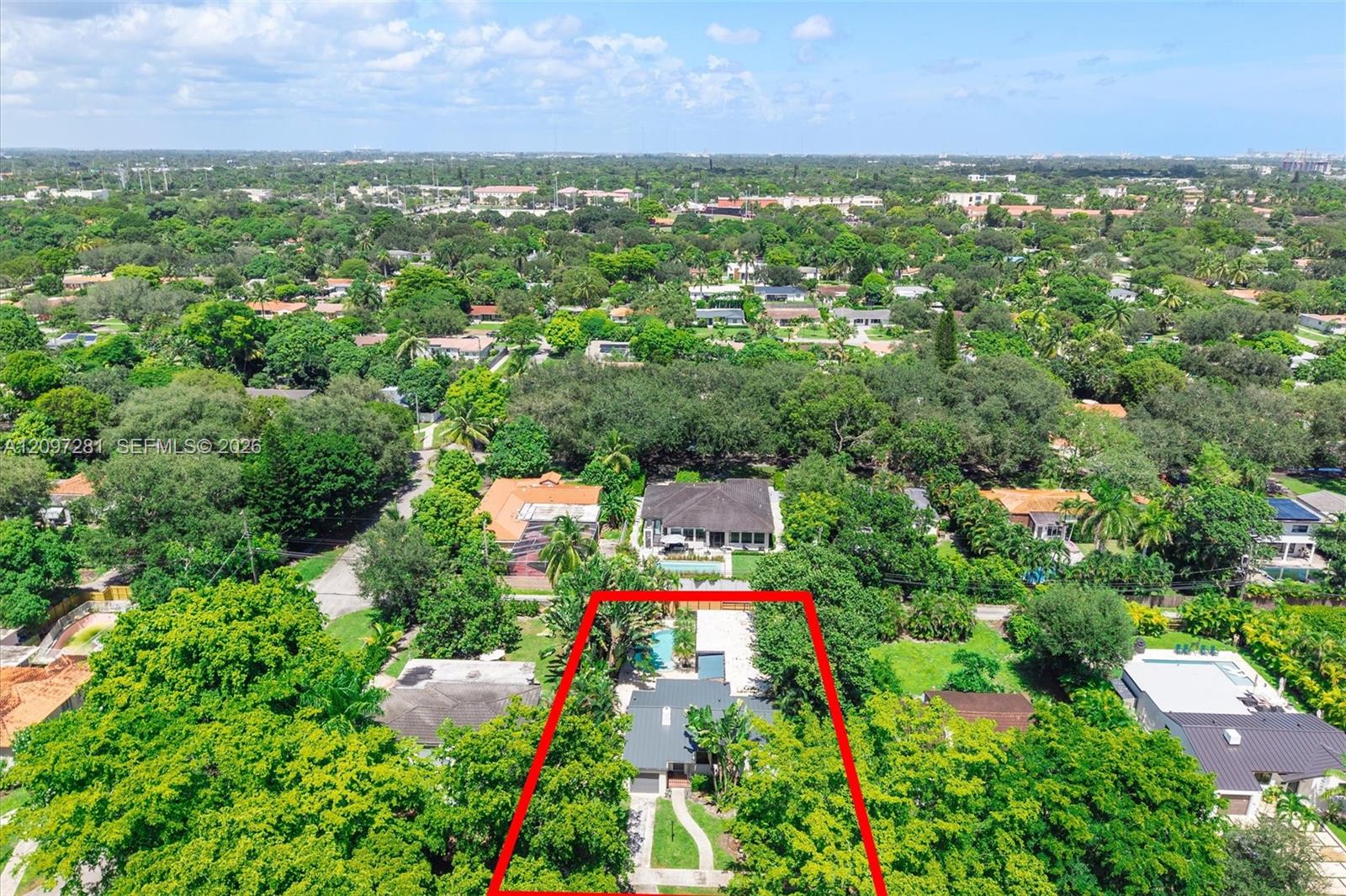 Aerial view of a Miami Shores home and pool within a red-outlined lot among leafy neighboring properties.