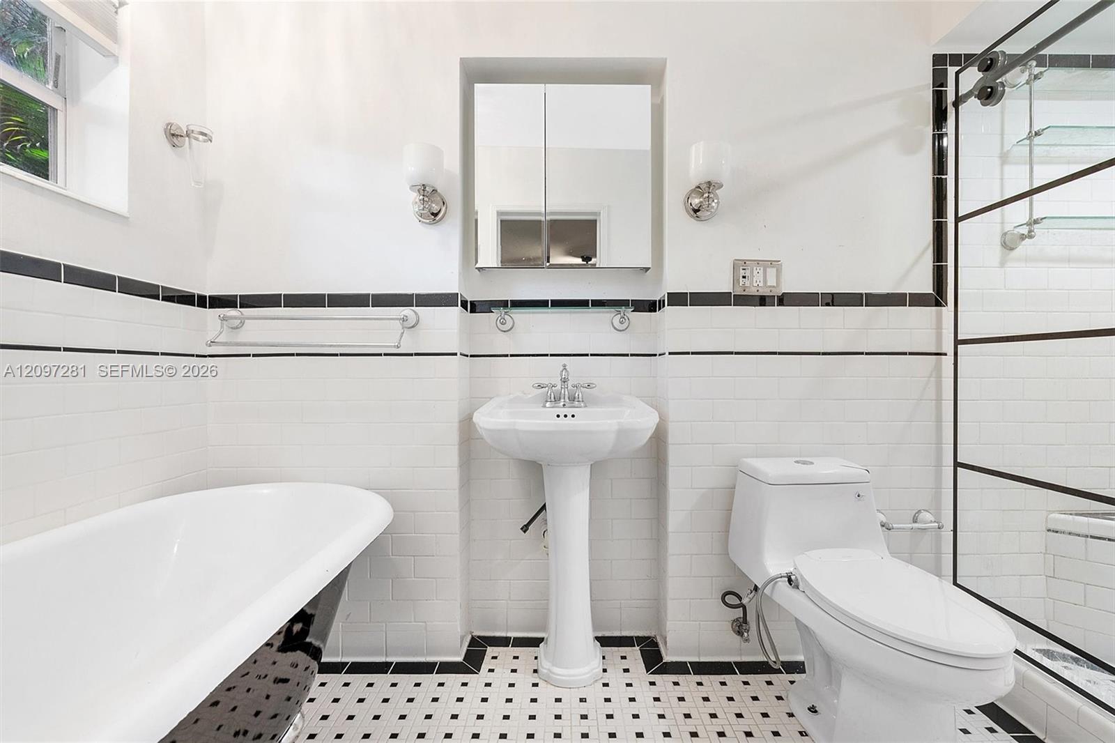 Bathroom with a freestanding tub, pedestal sink, and glass-enclosed shower.