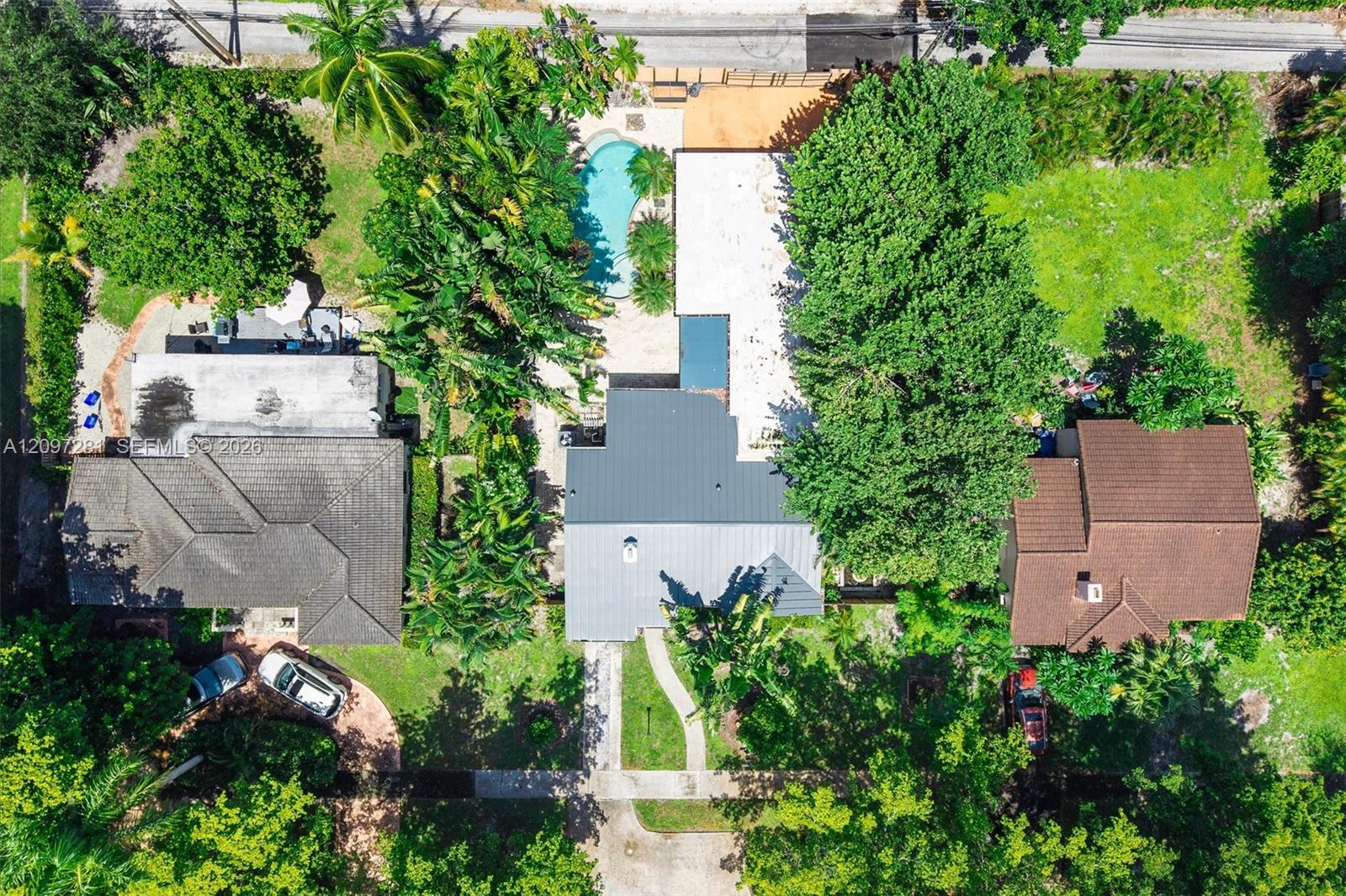 Aerial view of the house, swimming pool, and tropical landscaping.
