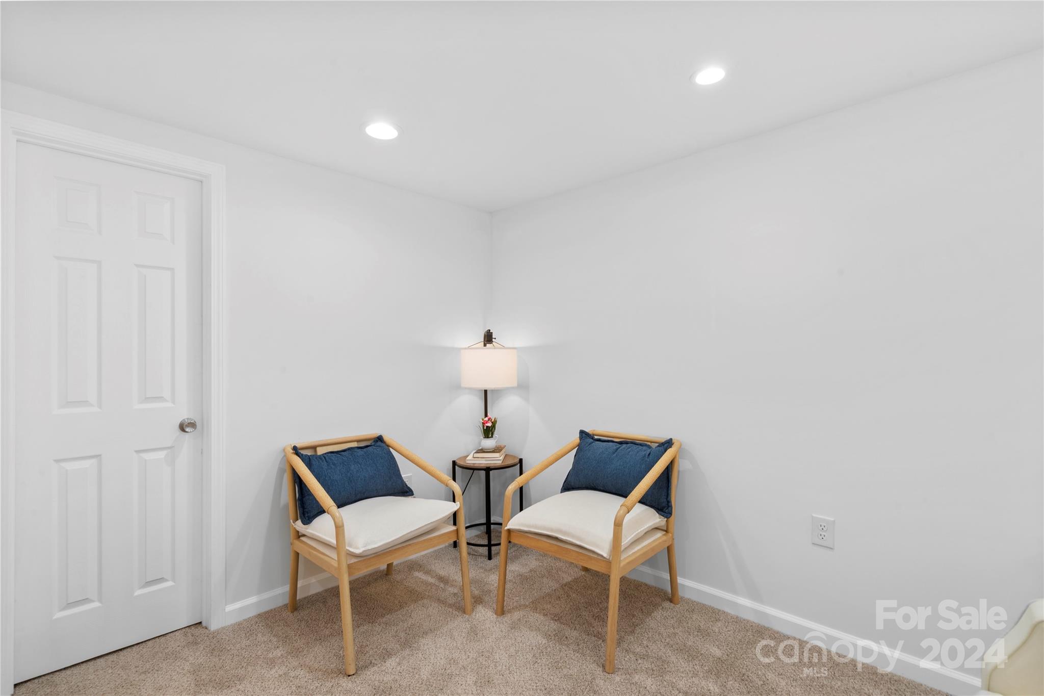 Two wood-framed chairs with navy cushions and a lamp create a small seating nook.