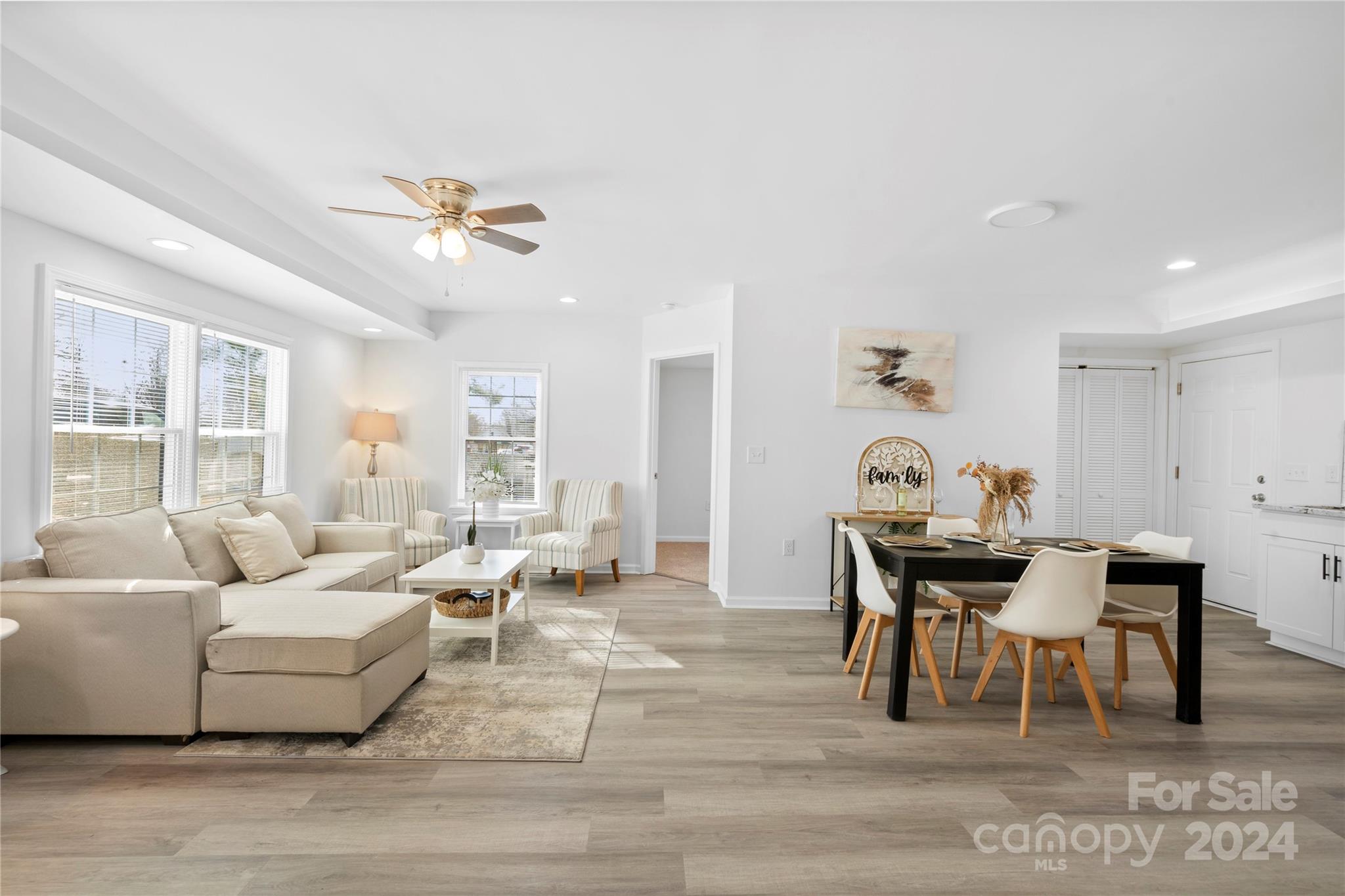 Open-plan living and dining room with a beige sectional, striped armchairs, and black dining table.