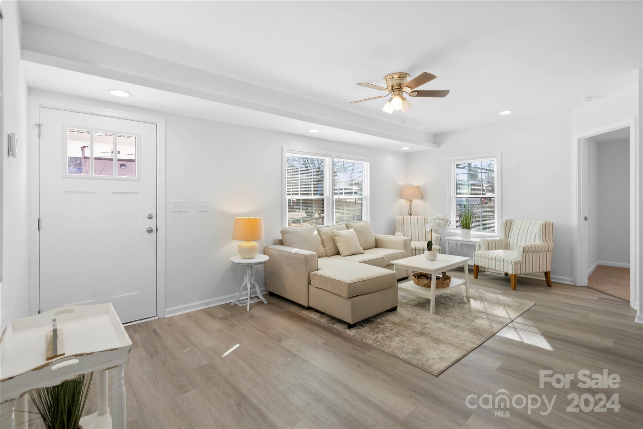 Staged living room with a beige sectional, striped armchairs, and large windows.