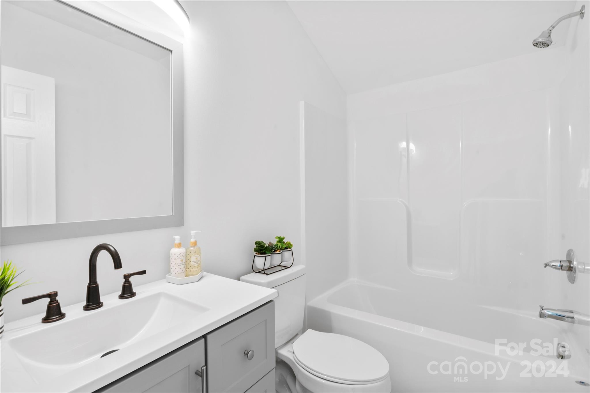 Bathroom with white vanity, dark bronze faucet, toilet, and tub-shower surround.