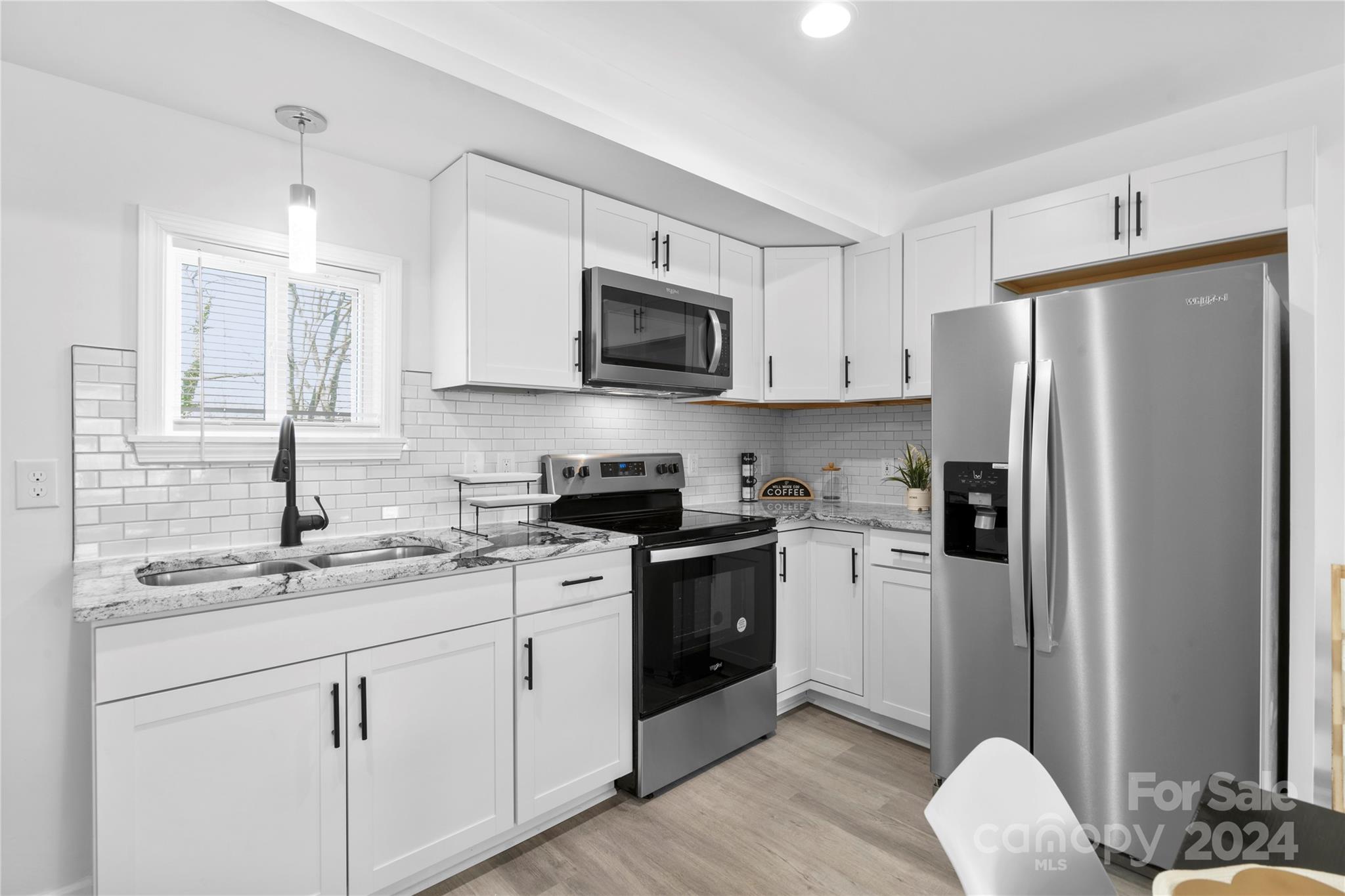 Kitchen with white cabinets, subway tile backsplash, marble-look counters, and stainless steel appliances.