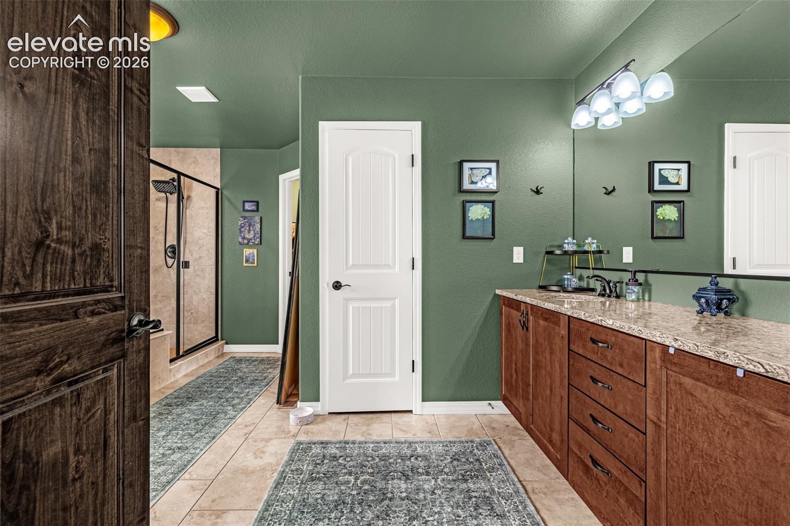 Bathroom with a wood double-sink vanity, large mirror, and glass-enclosed tiled shower.