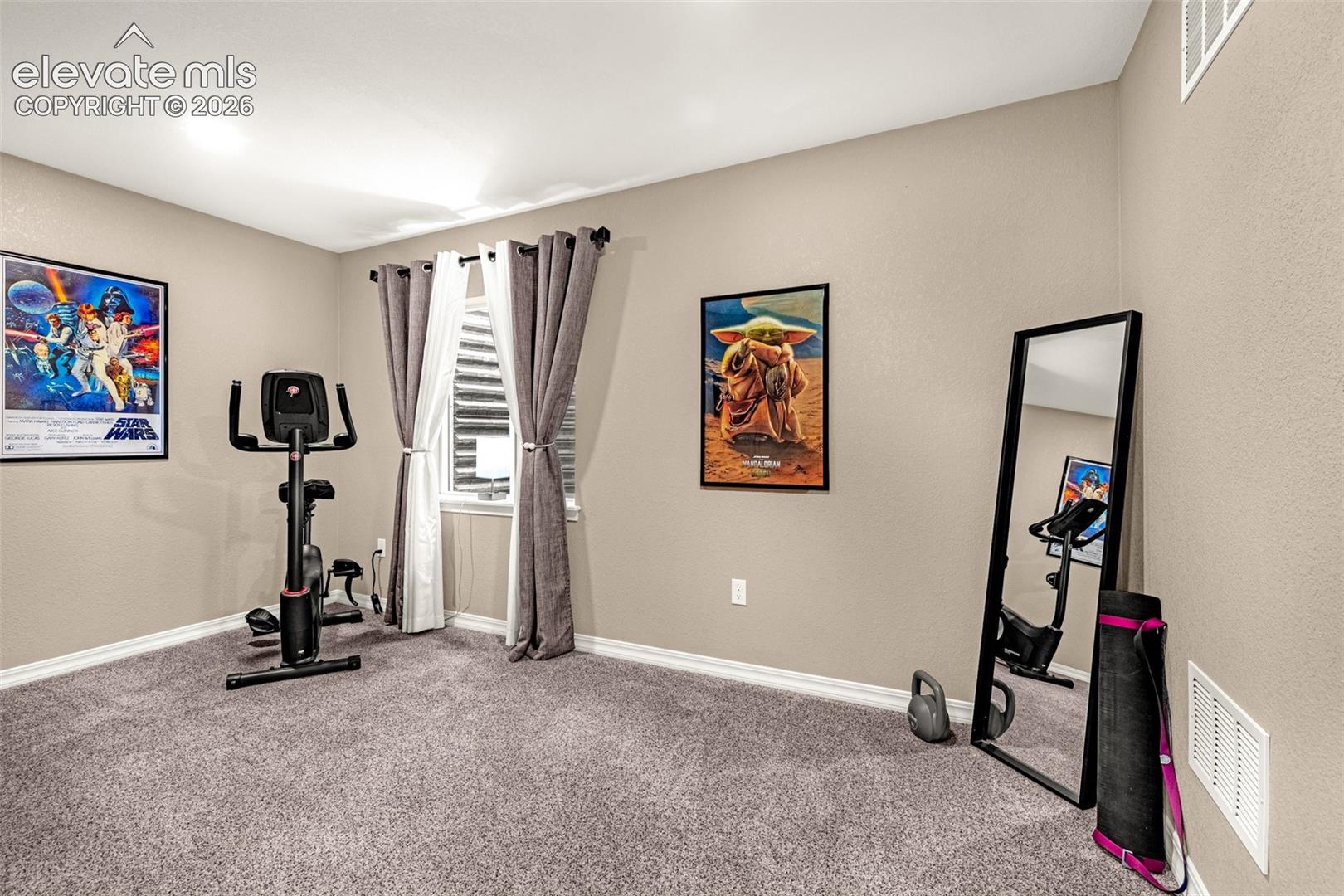 Home exercise room with a stationary bike, full-length mirror, and framed Star Wars posters.