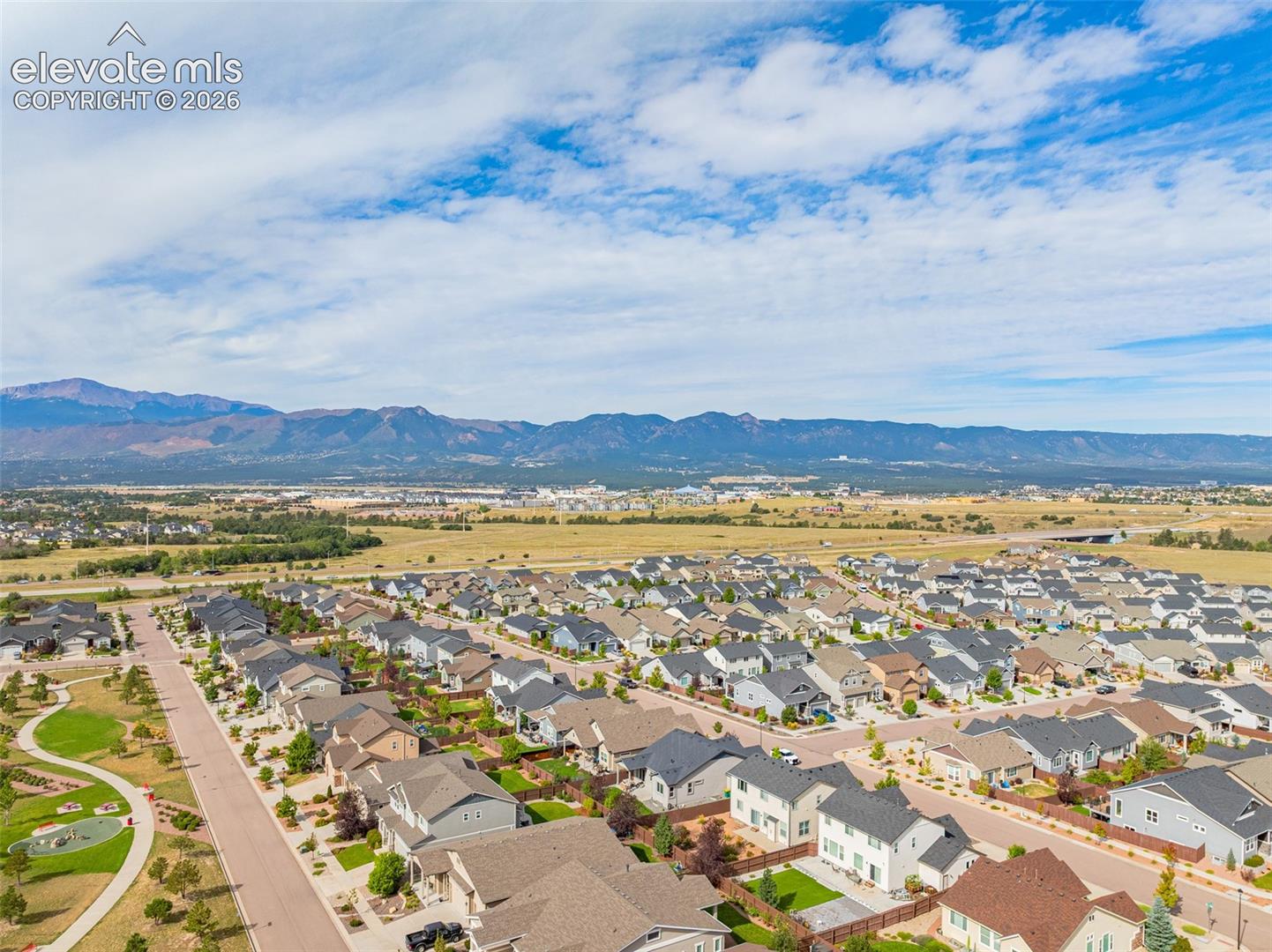 Aerial view of a Colorado Springs neighborhood with homes in the foreground and mountains on the horizon.