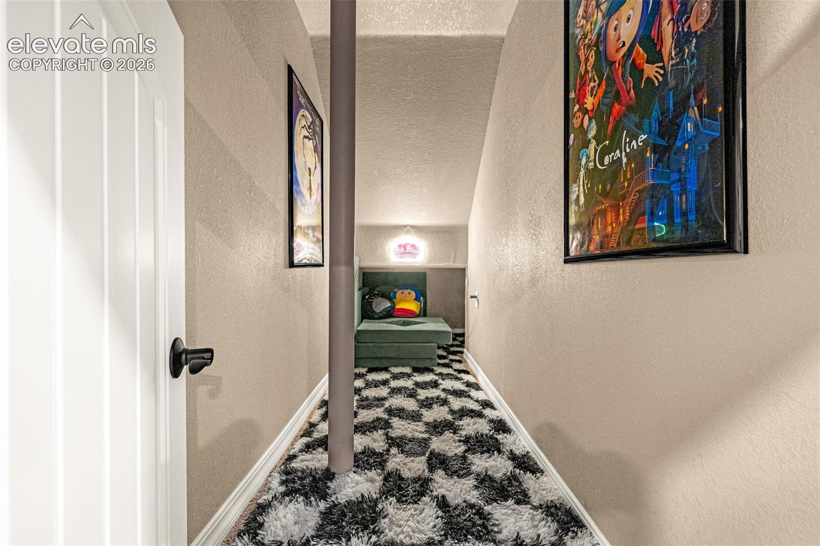 Furnished hallway with a black-and-white shag runner, support post, and Coraline poster.