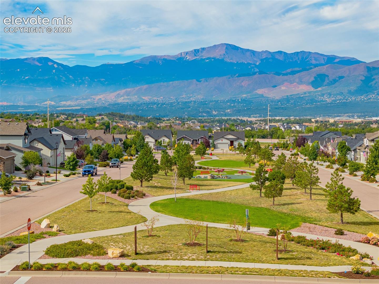 Residential neighborhood and park with a broad mountain range in the distance.
