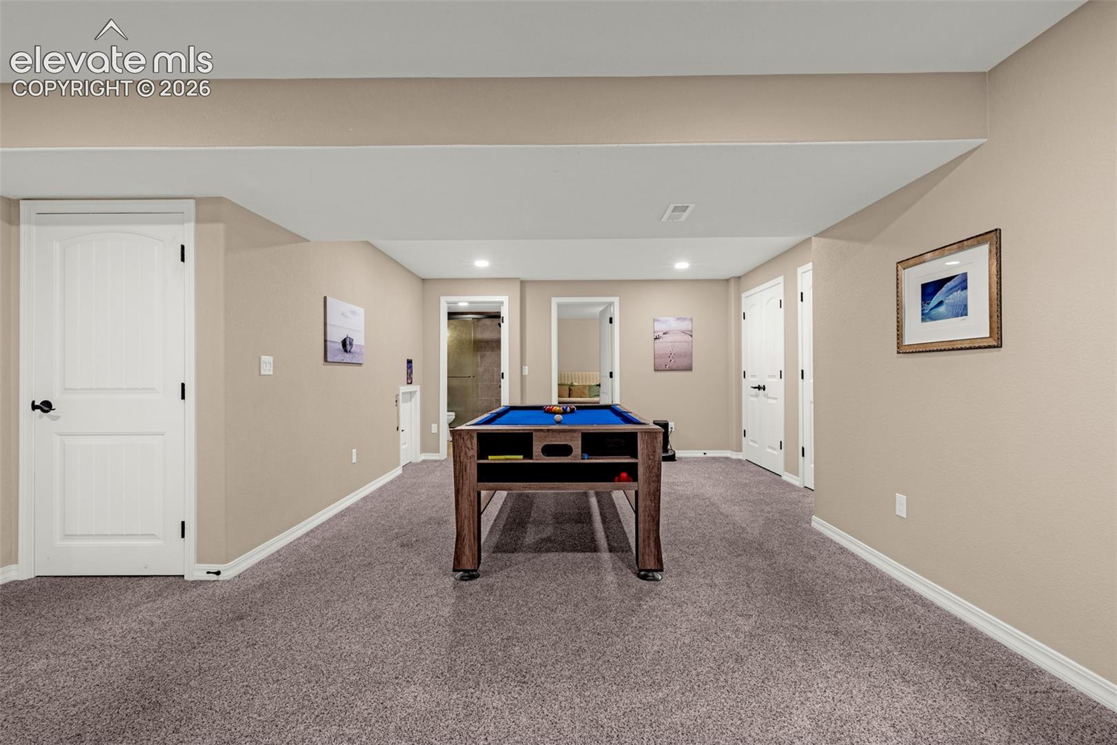 Basement game room with a blue-felt pool table and carpeted floor.