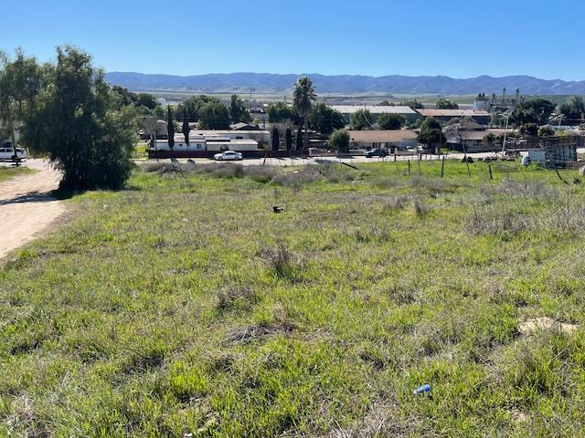 Grassy vacant lot with nearby homes and distant mountains.