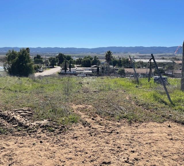 Vacant hillside lot with graded dirt, sparse brush, and distant mountain views.