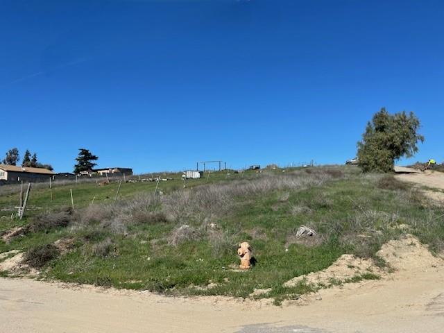 Grassy vacant hillside parcel beside a dirt road, with fencing and a fire hydrant.