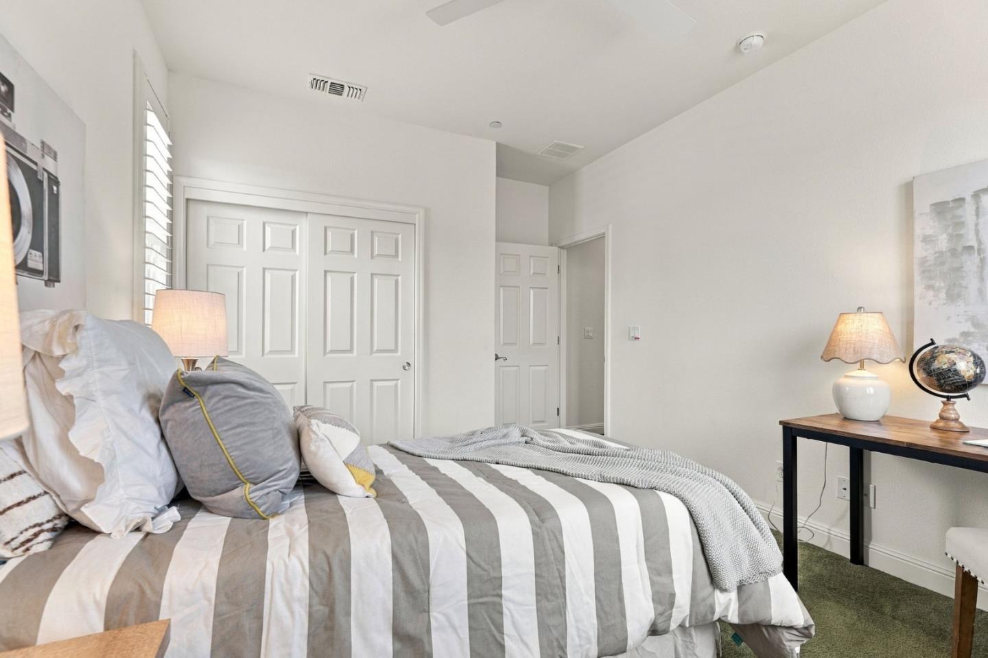 Furnished bedroom with gray-and-white striped bedding and white paneled closet doors.