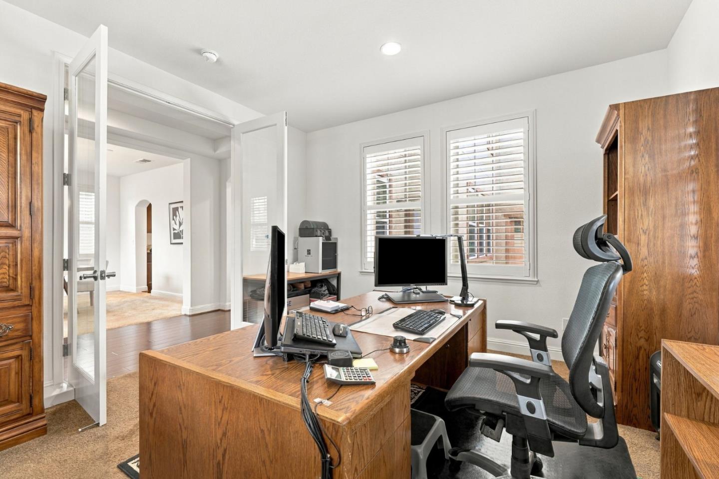 Home office with a large wooden desk, multiple monitors, and an ergonomic chair.