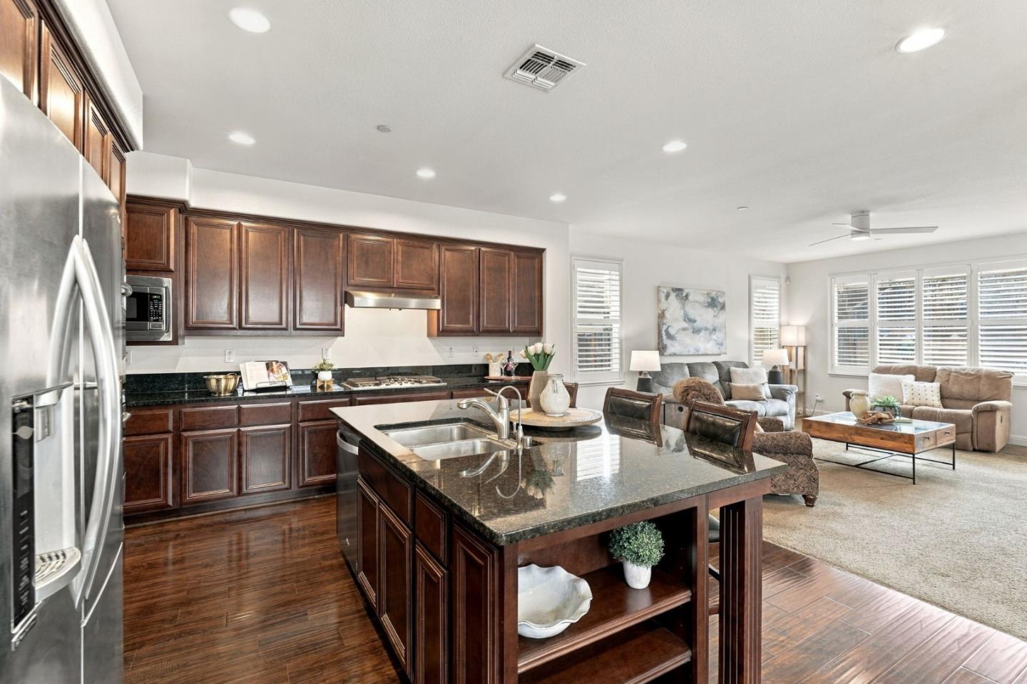 Open-plan kitchen with a dark wood island and granite counters beside a bright living room.