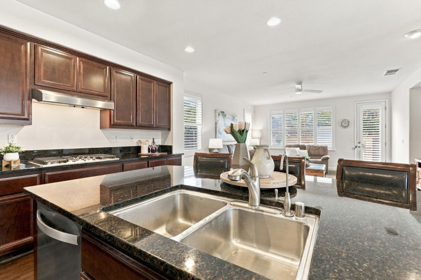 Kitchen with dark wood cabinets, granite counters, and a large island with a double-basin sink.