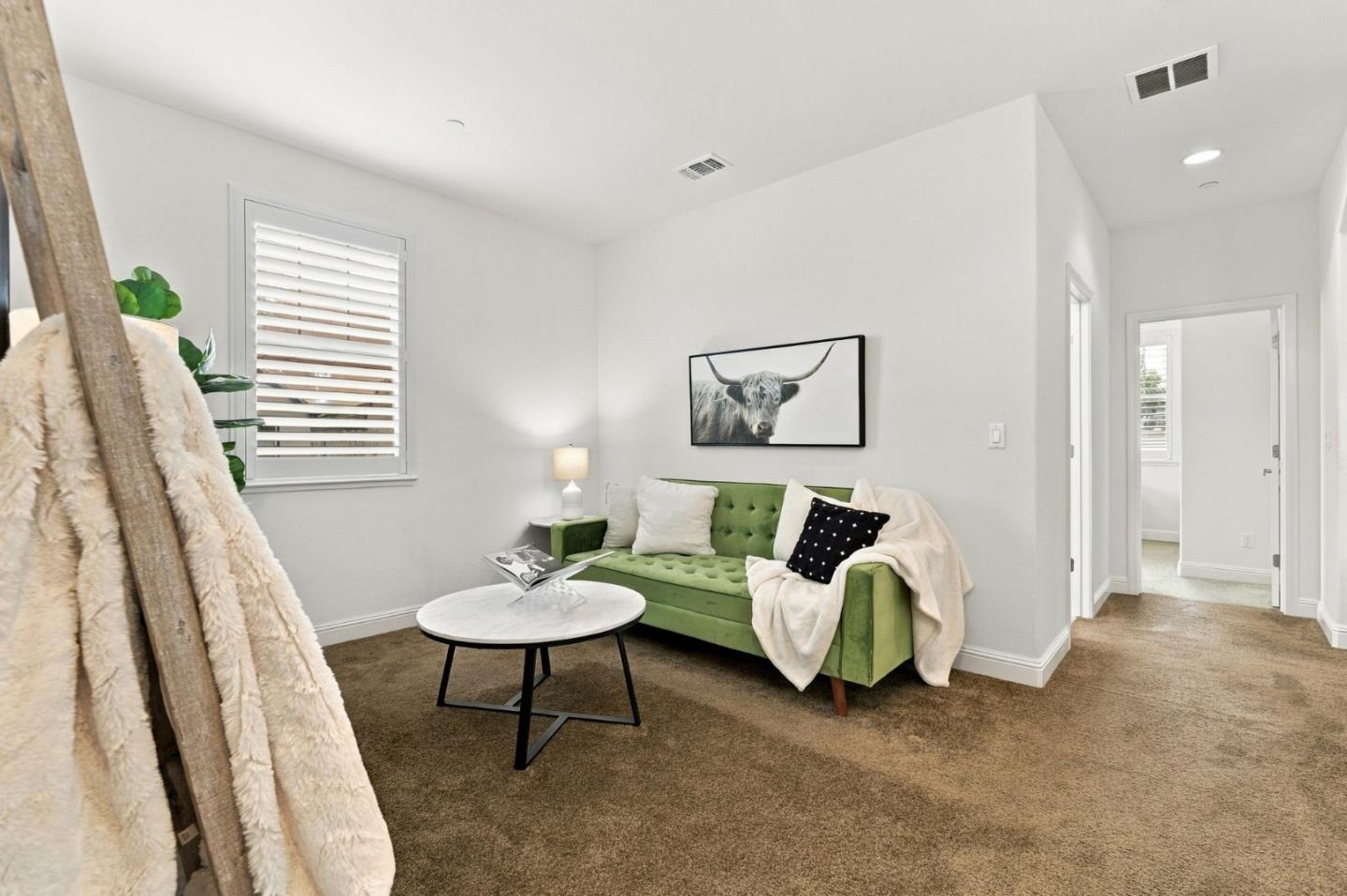 Sitting room with a green tufted sofa, round coffee table, and framed longhorn print.