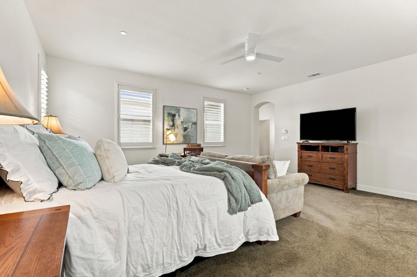 Bedroom with a large white bed, teal accents, a sofa, and a television.