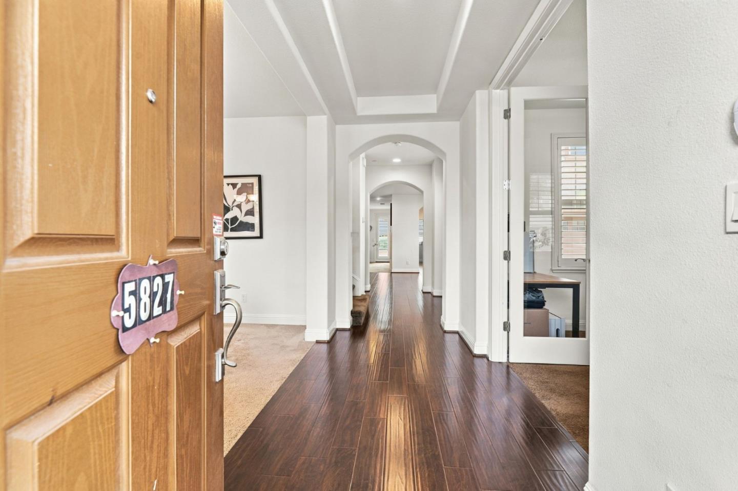 Entry hall with dark wood flooring, arched openings, and an open front door.