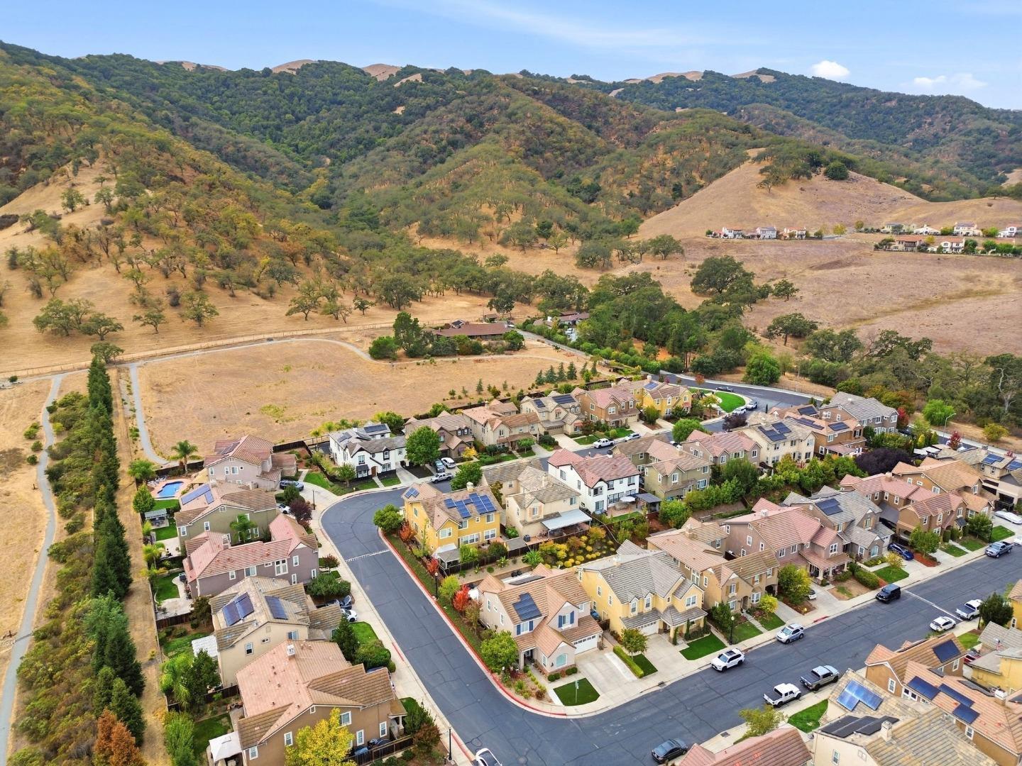 Aerial view of homes beside rolling, partly wooded hills.