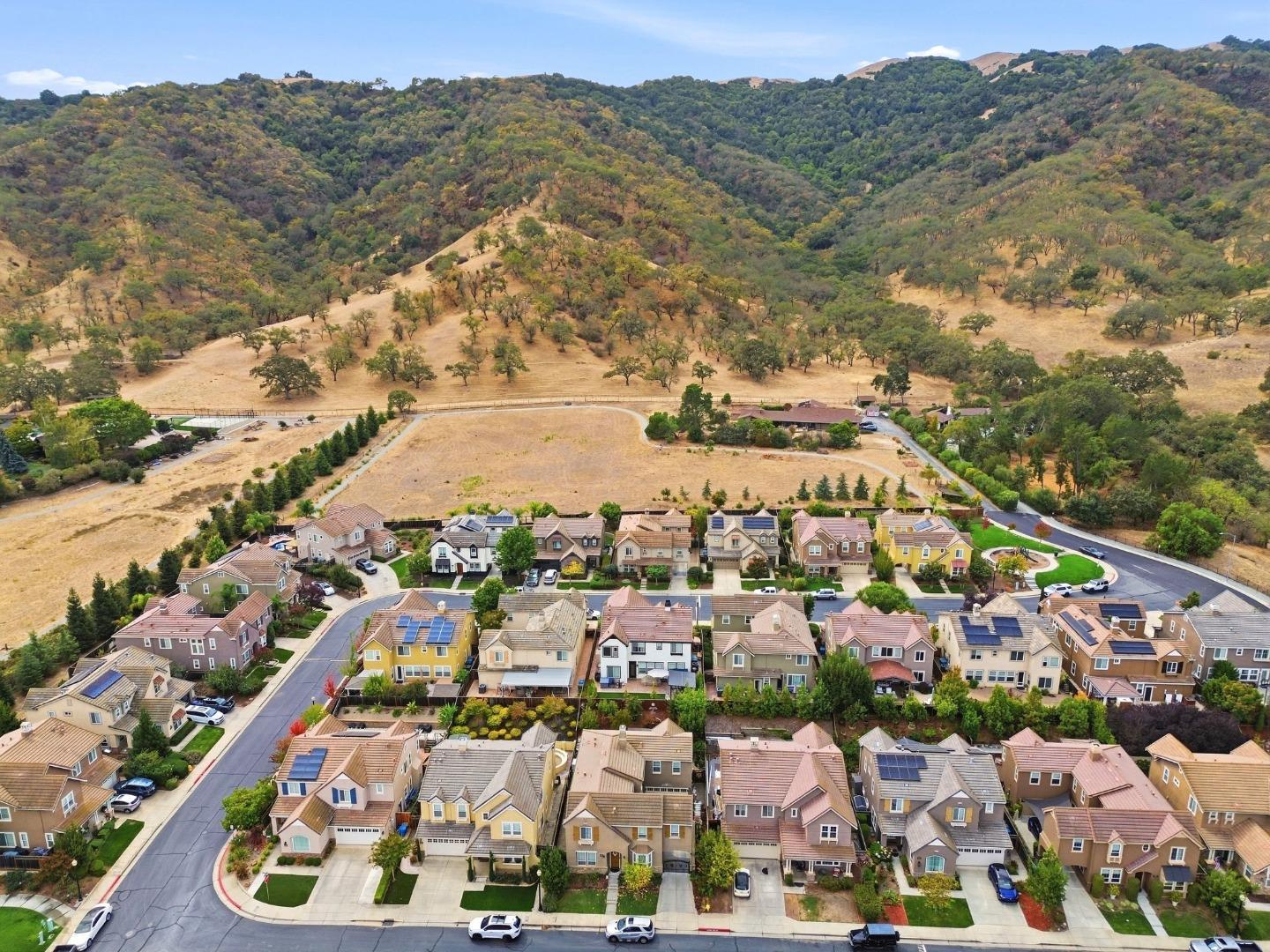 Aerial view of homes below rolling, tree-covered hills.