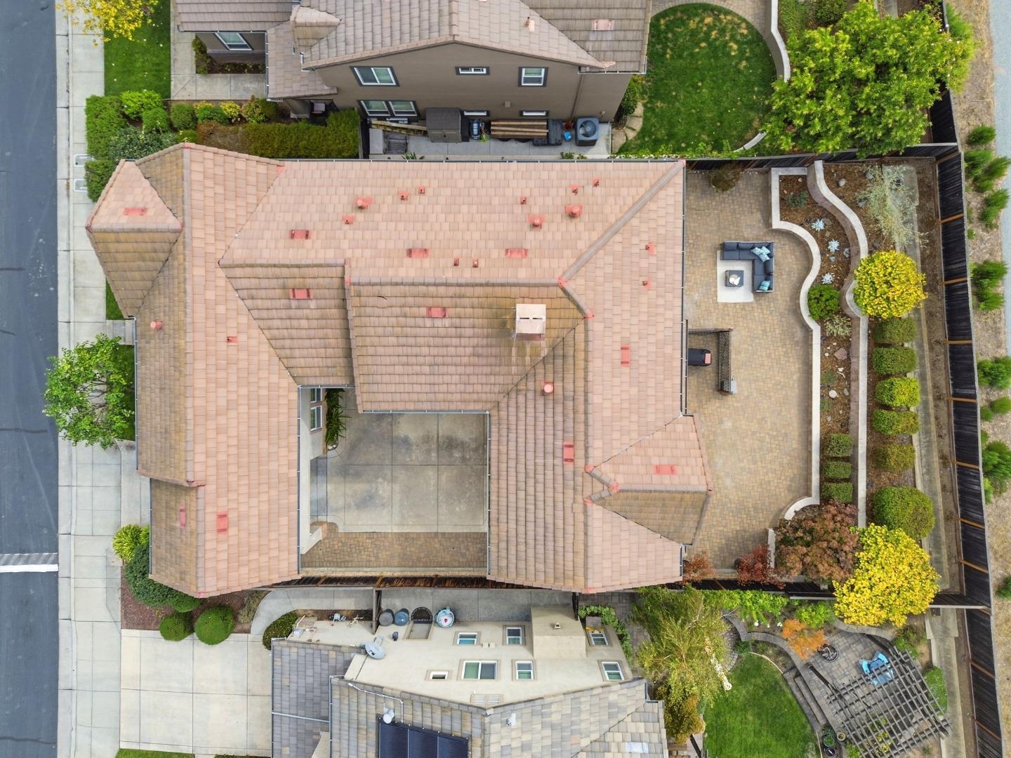 Aerial view of the home, tiled roof, landscaped courtyard, and paved patio.
