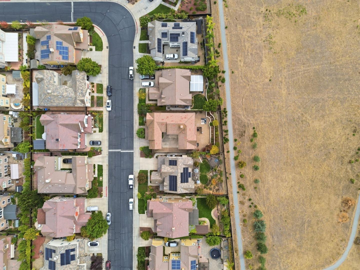 Aerial view of homes along a residential street beside a large open field.