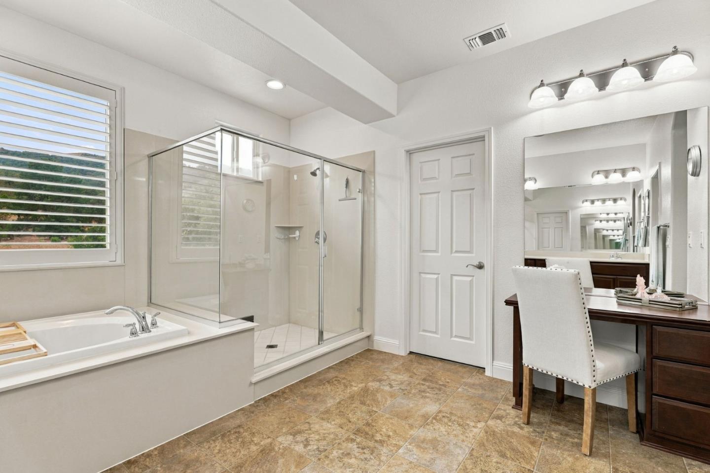 Bathroom with a soaking tub, glass shower, shuttered window, and dark wood vanity desk.