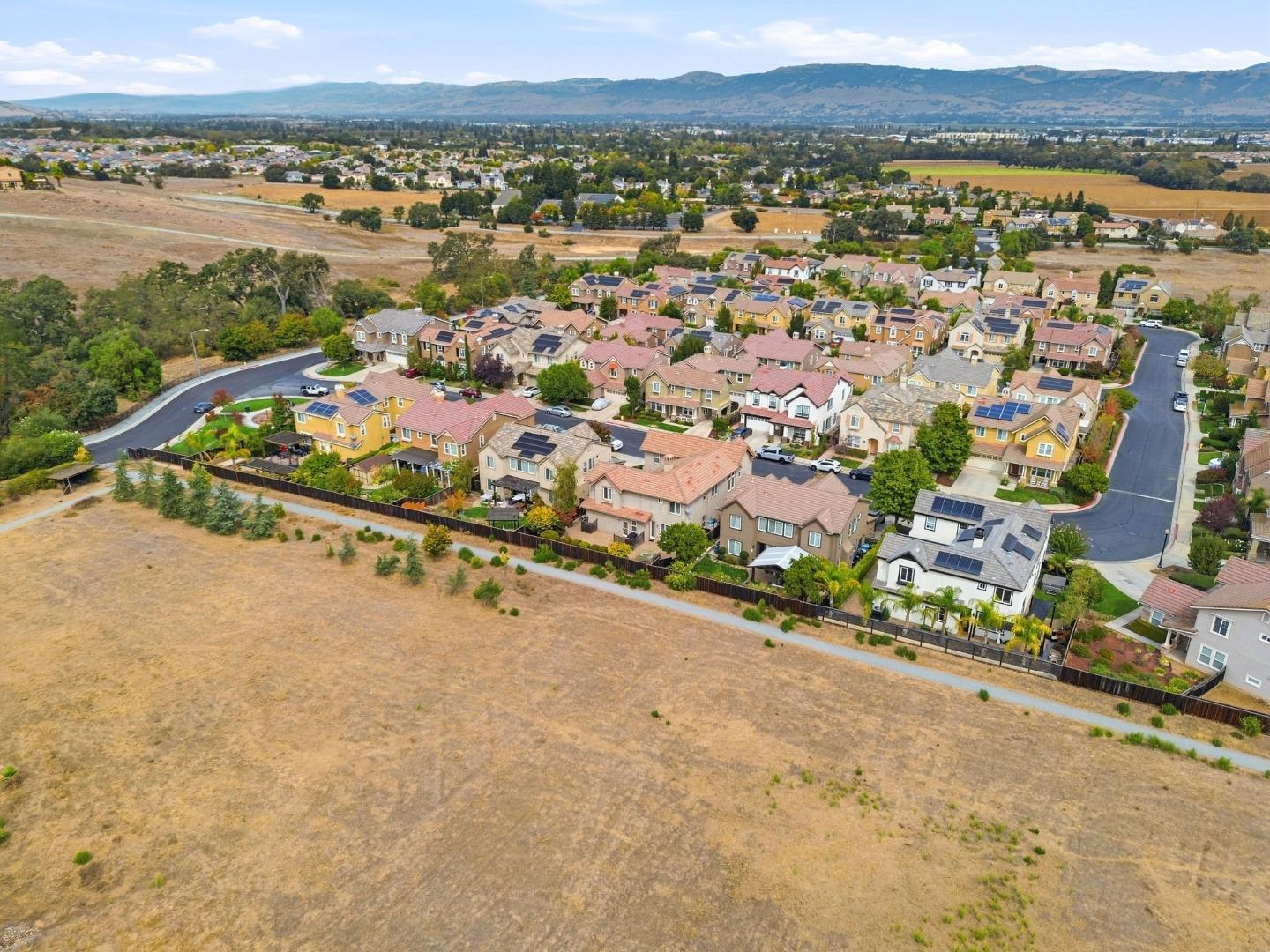 Aerial view of a residential neighborhood bordered by dry fields, with mountains in the distance.