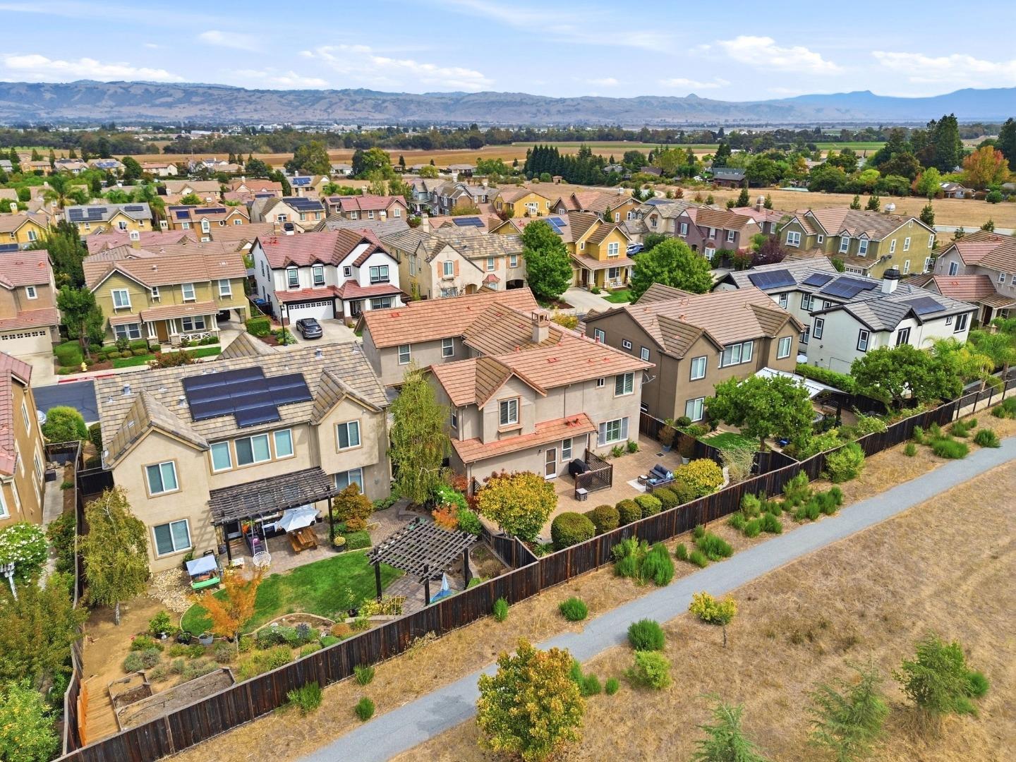 Aerial view of a residential neighborhood with fenced backyards and distant rolling hills.