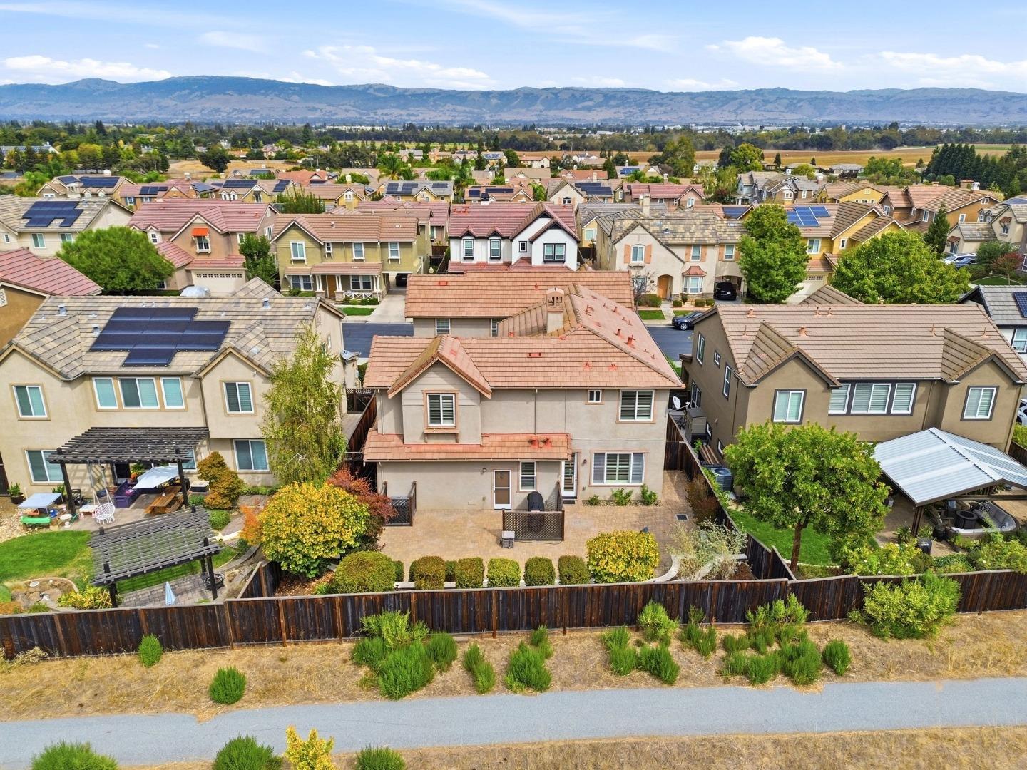 Aerial view of a two-story home and landscaped backyard, with neighborhood rooftops and mountains beyond.
