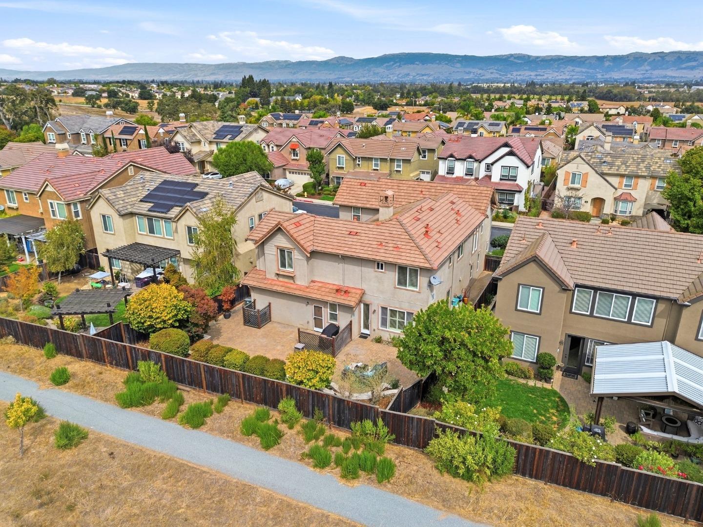 Aerial view of a suburban home among tiled-roof houses, with a mountain range beyond.